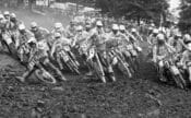 A talented field of riders charge into the first turn at the start of Moto 1 at the 1986 AMA 125cc Motocross National at Lake Sugar Tree MX Park in Axton, Virginia.