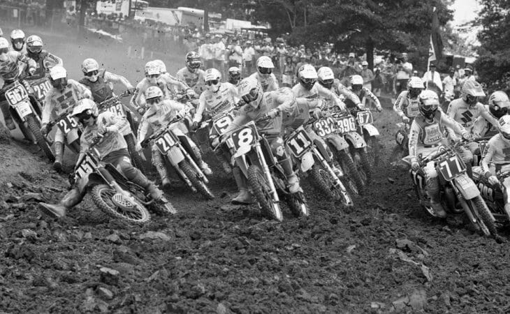 A talented field of riders charge into the first turn at the start of Moto 1 at the 1986 AMA 125cc Motocross National at Lake Sugar Tree MX Park in Axton, Virginia.
