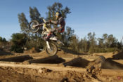 Colton Haaker jumping through the logs on his Husqvarna motorcycle.