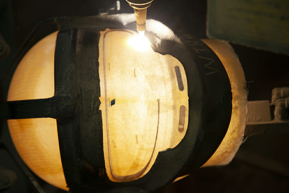 A machine laser cuts the eyeport on an Arai helmet.